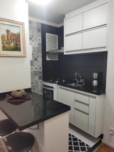 库里提巴Century Hall的厨房配有白色橱柜和黑色台面