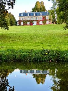 Château de Belleaucourt的田野上带池塘的大房子