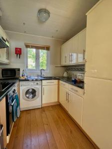 南塞尔尼The Cotswolds Lakeside - Kinsale Lodge,Spring Lake的厨房配有白色橱柜和洗衣机。
