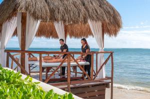 莫雷洛斯港Desire Riviera Maya Resort All Inclusive - Couples Only的坐在海滩上床边的男人和女人