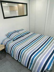 蒙特龙莱班Appartement dans maison atypique的一张带蓝白色条纹被子和镜子的床