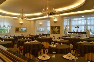 米兰马瑞提那Hotel Europa Milano Marittima的餐厅设有黑色桌椅和钢琴
