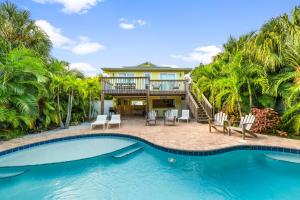 安娜玛丽亚Cabana Breeze的一座带游泳池和棕榈树的房子