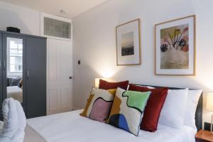 伦敦kings cross St Pancras luxury apt的卧室配有白色的床和色彩缤纷的枕头