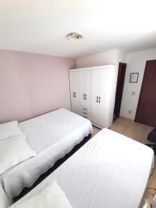 卡波布里奥Suítes Brisa Tropical的一间卧室设有两张床和白色橱柜。