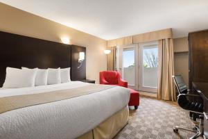 北湾Days Inn & Suites by Wyndham North Bay Downtown的酒店客房,配有一张床和一张红色椅子