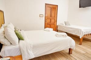 拉斯彭尼塔斯Aaki Hotel的一间卧室配有两张带白色床单的床
