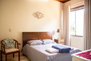 圣湖镇Casa das Pedras的卧室配有床、椅子和窗户。