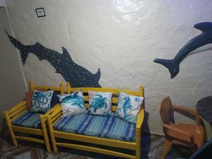 萨利诺波利斯Kitnet no Farol Velho的客房设有带枕头的长凳和墙上涂有海豚的墙壁