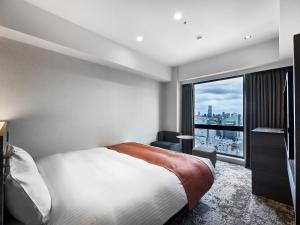 大阪DEL style Osaka-Shinsaibashi by Daiwa Roynet Hotel的一间卧室设有一张床和一个大窗户