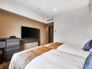 大阪DEL style Osaka-Shinsaibashi by Daiwa Roynet Hotel的酒店客房设有两张床和一台平面电视。