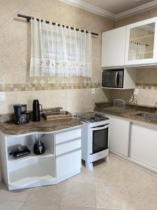 卡波布里奥Ótima Casa com Piscina, Sauna e Churrasqueira的厨房配有白色橱柜和炉灶烤箱。