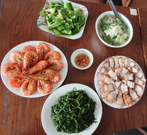 富国Xan hotel Phu Quoc的一张桌子上放有虾和蔬菜的盘子