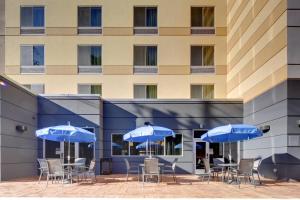 阿什维尔Fairfield Inn & Suites by Marriott Asheville Tunnel Road的大楼前方的带椅子和蓝色遮阳伞的天井