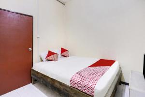 JodohSPOT ON 91422 Ringin Pitu 2 Syariah的一张带红色和白色枕头的床