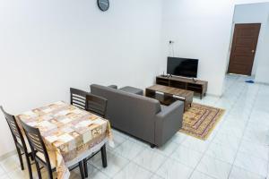 麻坡Tok Umi Guesthouse@AMJ Bakri的带沙发、桌子和电视的客厅