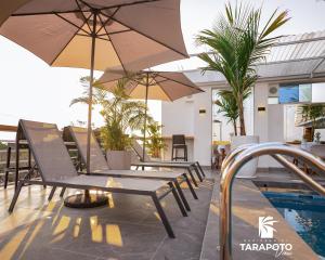 塔拉波托Residencial Tarapoto View的游泳池旁带椅子和遮阳伞的天井