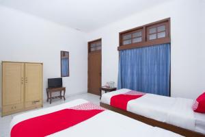 TimuranSuper OYO 759 Hotel Dewi Sri的一间卧室配有两张床和电视。