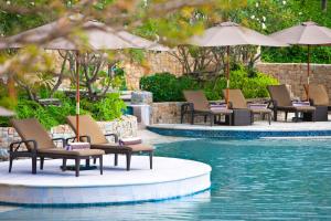 普吉镇The Westin Siray Bay Resort & Spa, Phuket的游泳池旁的一排椅子和遮阳伞