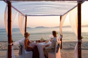 普吉镇The Westin Siray Bay Resort & Spa, Phuket的坐在海滩餐桌旁的一对夫妇