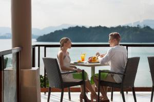 普吉镇The Westin Siray Bay Resort & Spa, Phuket的坐在阳台上桌子上的男人和女人