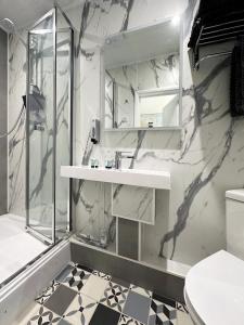 伦敦Kensington Studio hosted by AirOperate的白色的浴室设有水槽和淋浴。
