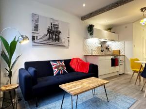 伦敦Kensington Studio hosted by AirOperate near Notting Hill - 1 Double Bed , 1 Sofa Bed, Ground Floor Apartment via Private Entrance的一间带蓝色沙发的客厅和一间厨房