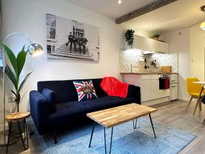 伦敦Kensington Studio hosted by AirOperate near Notting Hill - 1 Double Bed , 1 Sofa Bed, Ground Floor Apartment via Private Entrance的一间带蓝色沙发的客厅和一间厨房