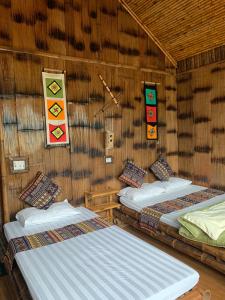 枚州县Mai Chau La Vida Homestay的一间设有两张位于稻草墙内床的房间