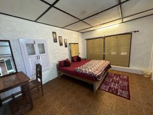 达兰萨拉Dreamwoods A travellers farmhouse的卧室位于客房的角落,配有一张床