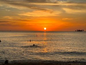 富国Tropical Bay Grand World Phu Quoc的海滩上的日落和水中的人