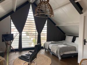 赞德沃特Villa Zandvoort的卧室配有一张床和一张椅子,位于窗户前