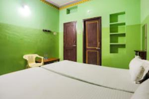 克塔克Indra Bhawan Lodge, Cuttack的卧室设有白色的床和绿色的墙壁