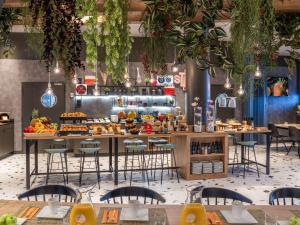 马德里Ibis Madrid Aeropuerto Barajas的餐厅设有桌椅,供应自助餐。