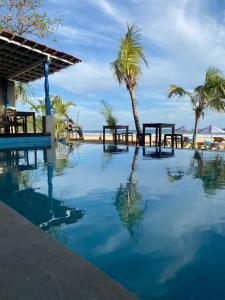 南塔拉拉塔拉拉湾海滩酒店的海滩上带桌子和棕榈树的游泳池