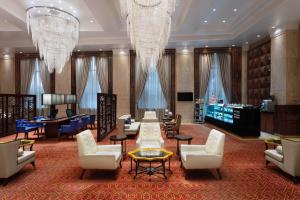 浦那Sheraton Grand Pune Bund Garden Hotel的酒店大堂设有椅子、桌子和吊灯。