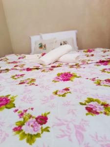 马拉戈日Cantinho da Rosy的白色棉被上带粉红色花的床铺