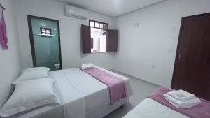 伦索伊斯Pousada Estrelar的白色的客房设有两张床和窗户。