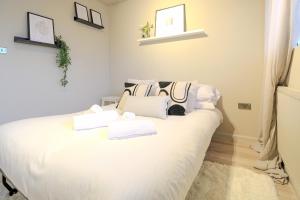 伦敦Sleeps 5 - King bed 2 bathrooms - Limehouse Station的卧室配有白色床和毛巾