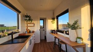 KillarneySunset Haven - port fairy tiny homes的一间小房子里的厨房,配有木柜台和窗户