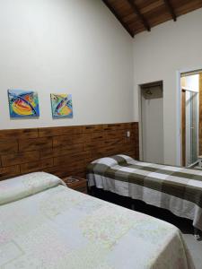 布希奥斯Pousada Alto da Marina的一间卧室配有两张床,墙上有两幅画作