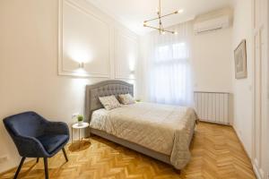 布达佩斯Luxurious Central 4BEDRM 3BATHRM Residence w/ Balcony的一间卧室配有一张床和一张蓝色椅子