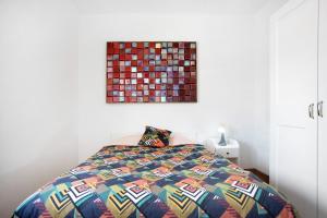卡尔达斯达·赖尼亚Apartamento da Alegria的卧室内一张带五颜六色棉被的床