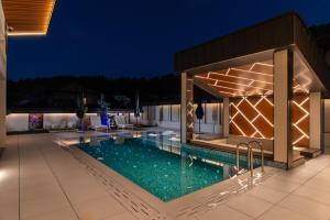 巴尼亚Alpine Bell Villa的夜间在房子里的一个游泳池