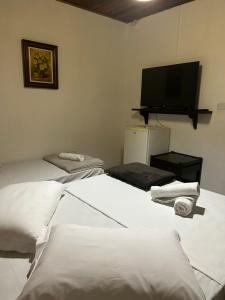 托雷斯Pousada House Sol & Praia的客房设有两张床和一台平面电视。