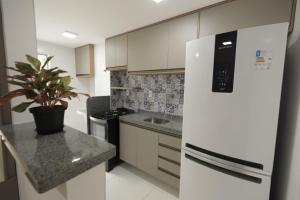 圣路易斯Apartamento Luxuoso à 2km da Litorânea的厨房配有白色冰箱和盆栽植物