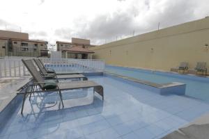 圣路易斯Apartamento Luxuoso à 2km da Litorânea的一座建筑物边带椅子的游泳池