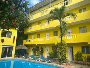 苏莎亚Coco Hotel and Hostel的一座黄色的建筑,前面有一个游泳池