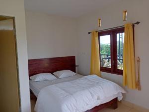 不拉士打宜Berastagi Mountain View Homestay & Pizzeria的卧室配有白色的床和窗户。
