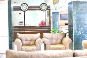 延布Safa PARK HOTEL YANBU فندق صفا بارك ينبع的大堂设有两把椅子和墙上的时钟